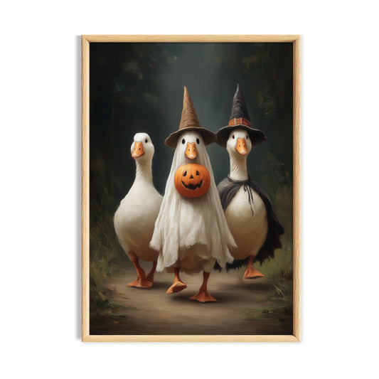 Three funny white geese in Halloween costumes with witch hats, a ghost costume and jack-o'-lantern pumpkin