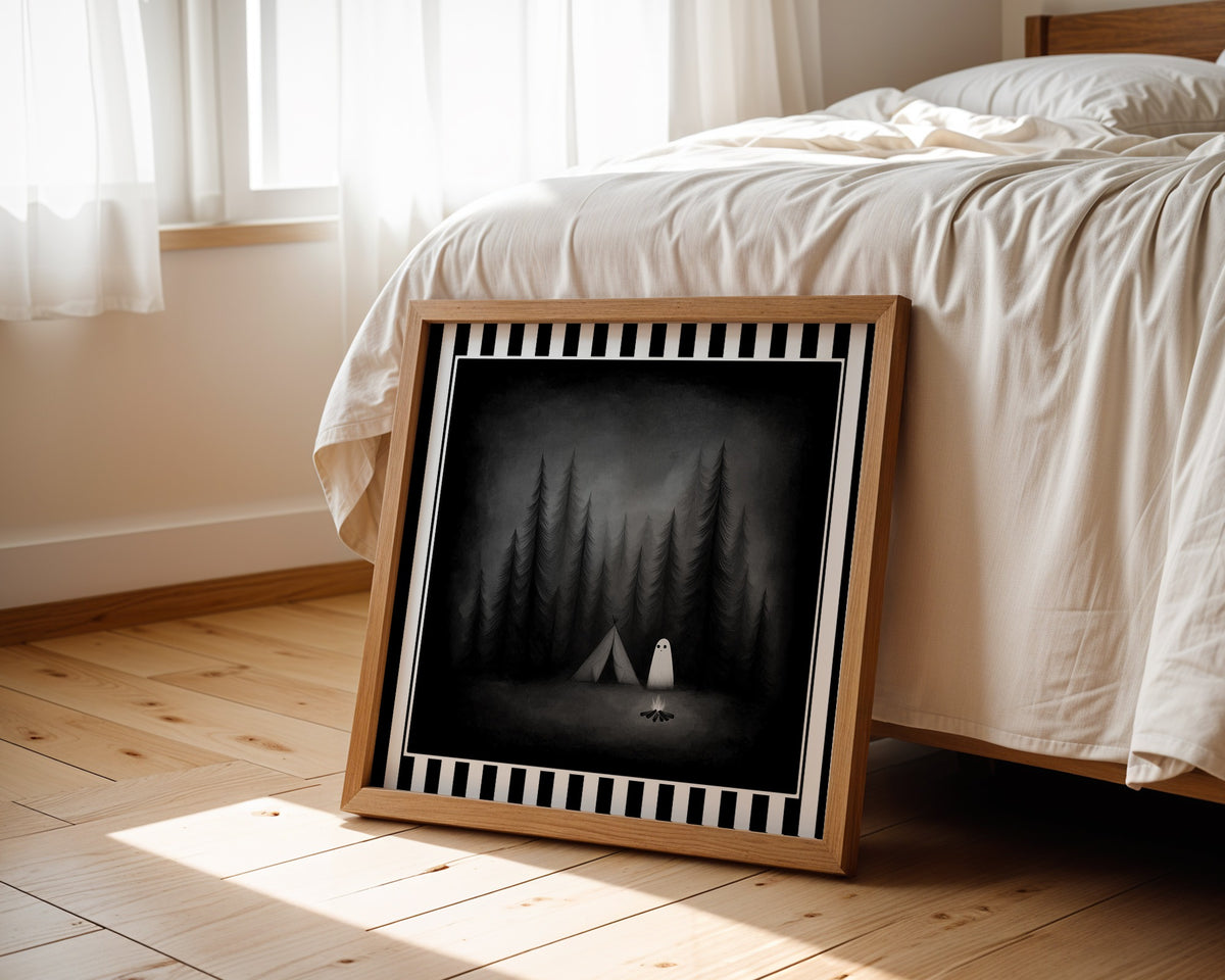Ghost camping gothic print in a light wood frame leaning beside a bed