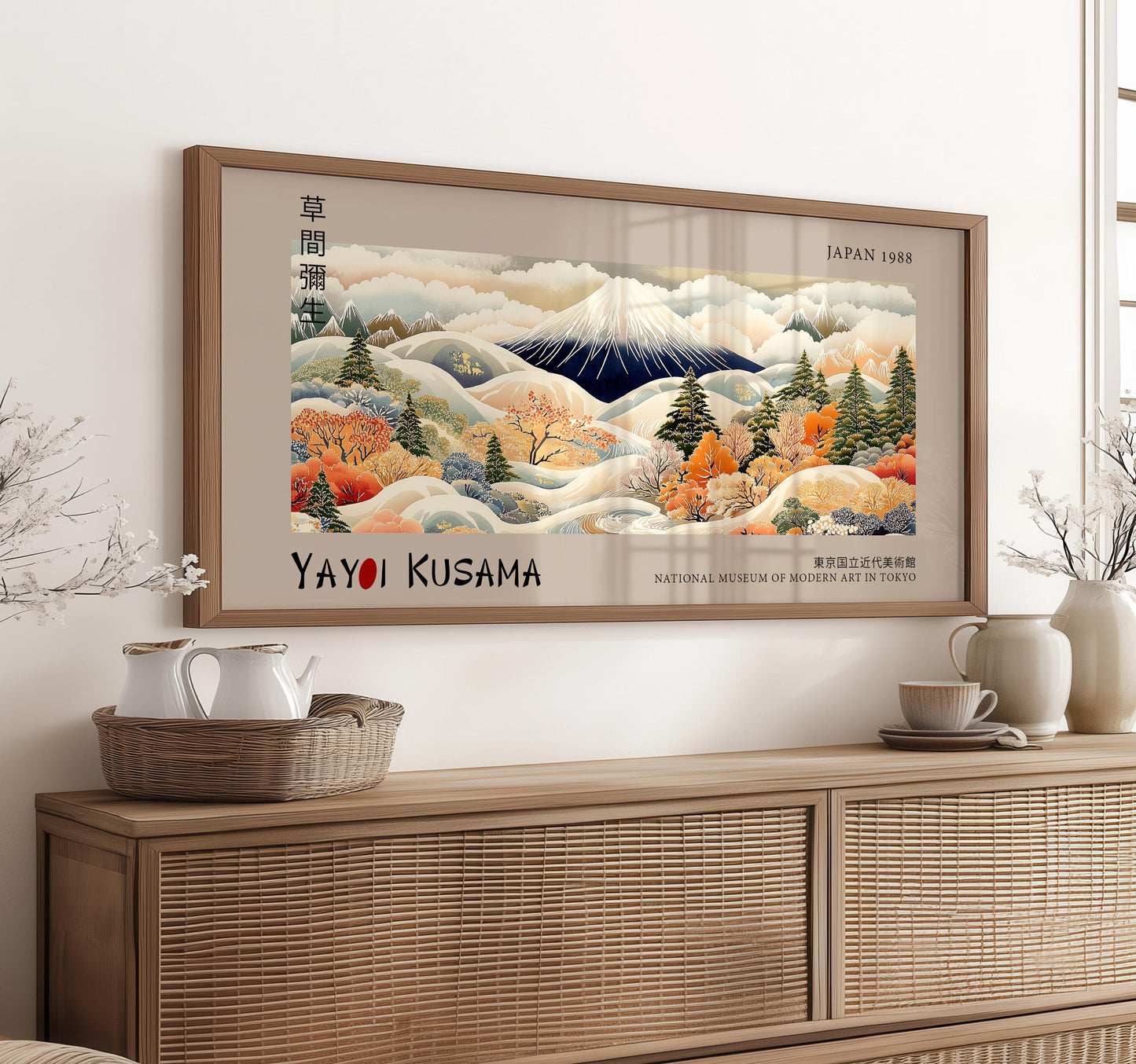 a framed painting of a mountainous landscape with autumnal trees, displayed on a wall above a wooden cabinet.