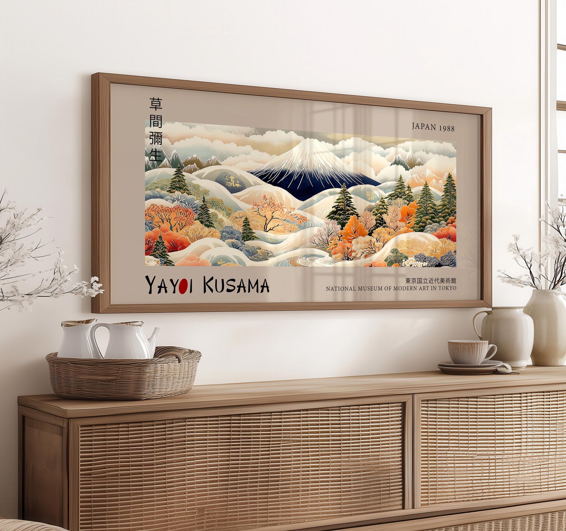 a framed painting of a mountainous landscape with autumnal trees, displayed on a wall above a wooden cabinet.