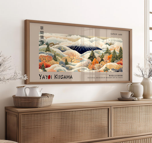 a framed painting of a mountainous landscape with autumnal trees, displayed on a wall above a wooden cabinet.