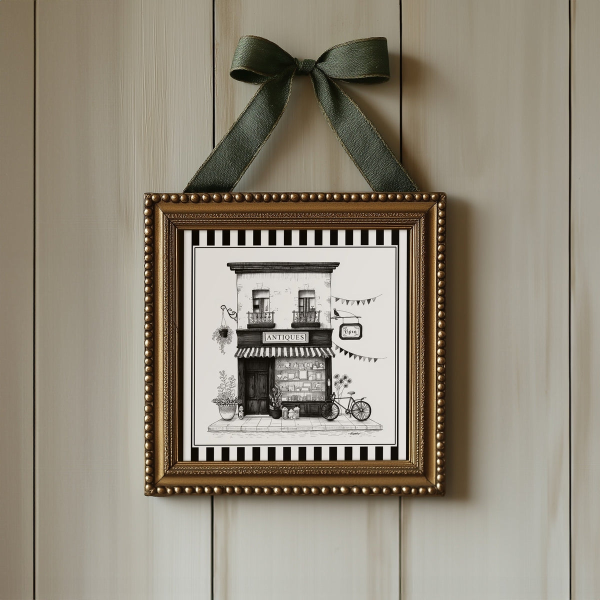 Black and white antique shop print displayed in an ornate gold square frame with ribbon