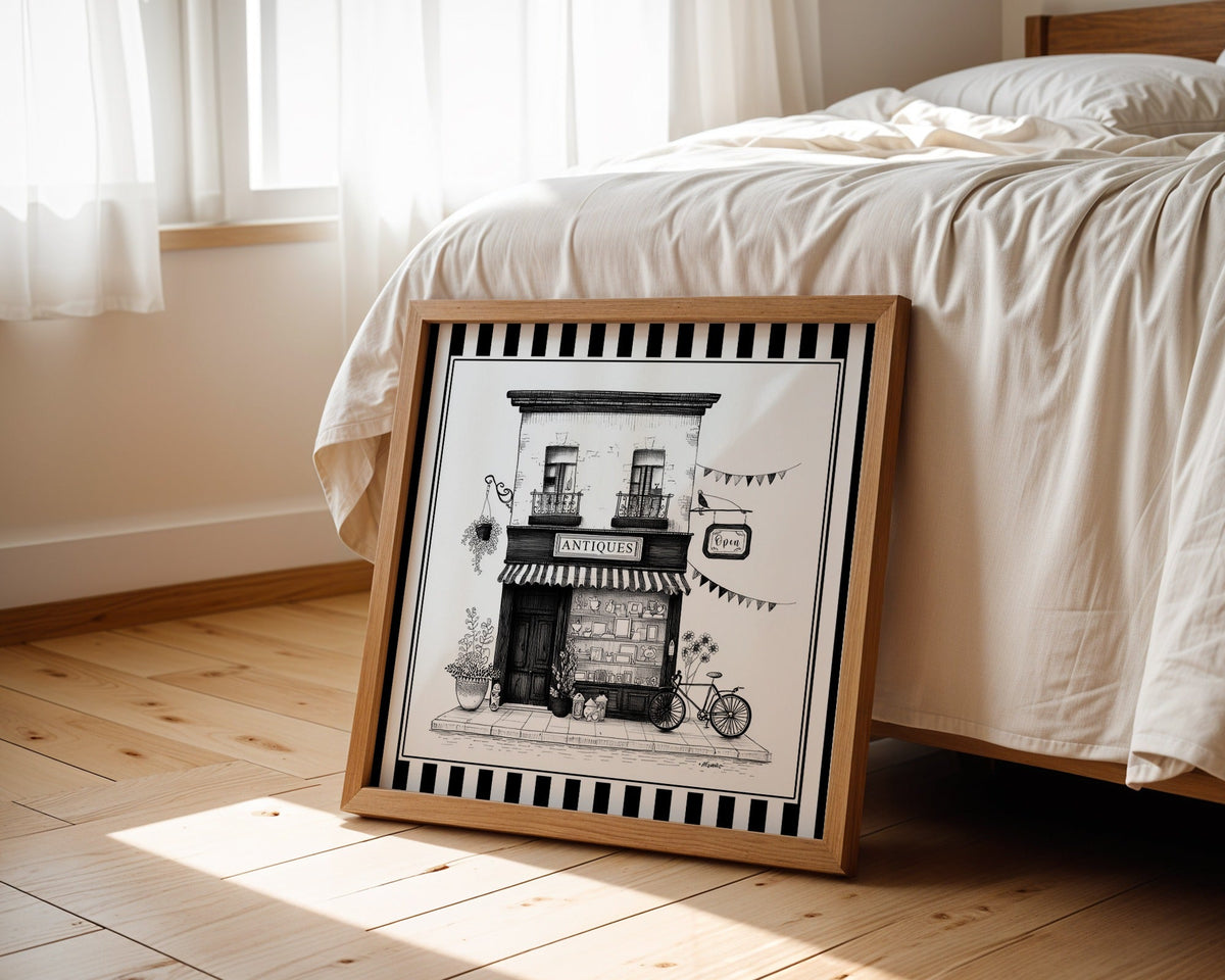 Black and white antique shop print displayed beside a bed in a light wood square frame