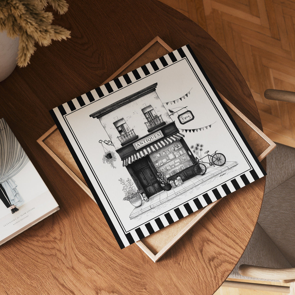 Square black and white antique shop print displayed flat on a wooden table