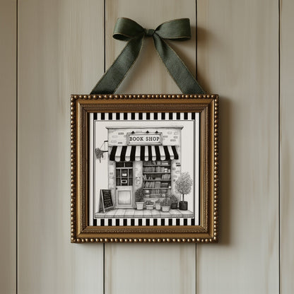 Black and white book shop print displayed in an ornate gold square frame with ribbon