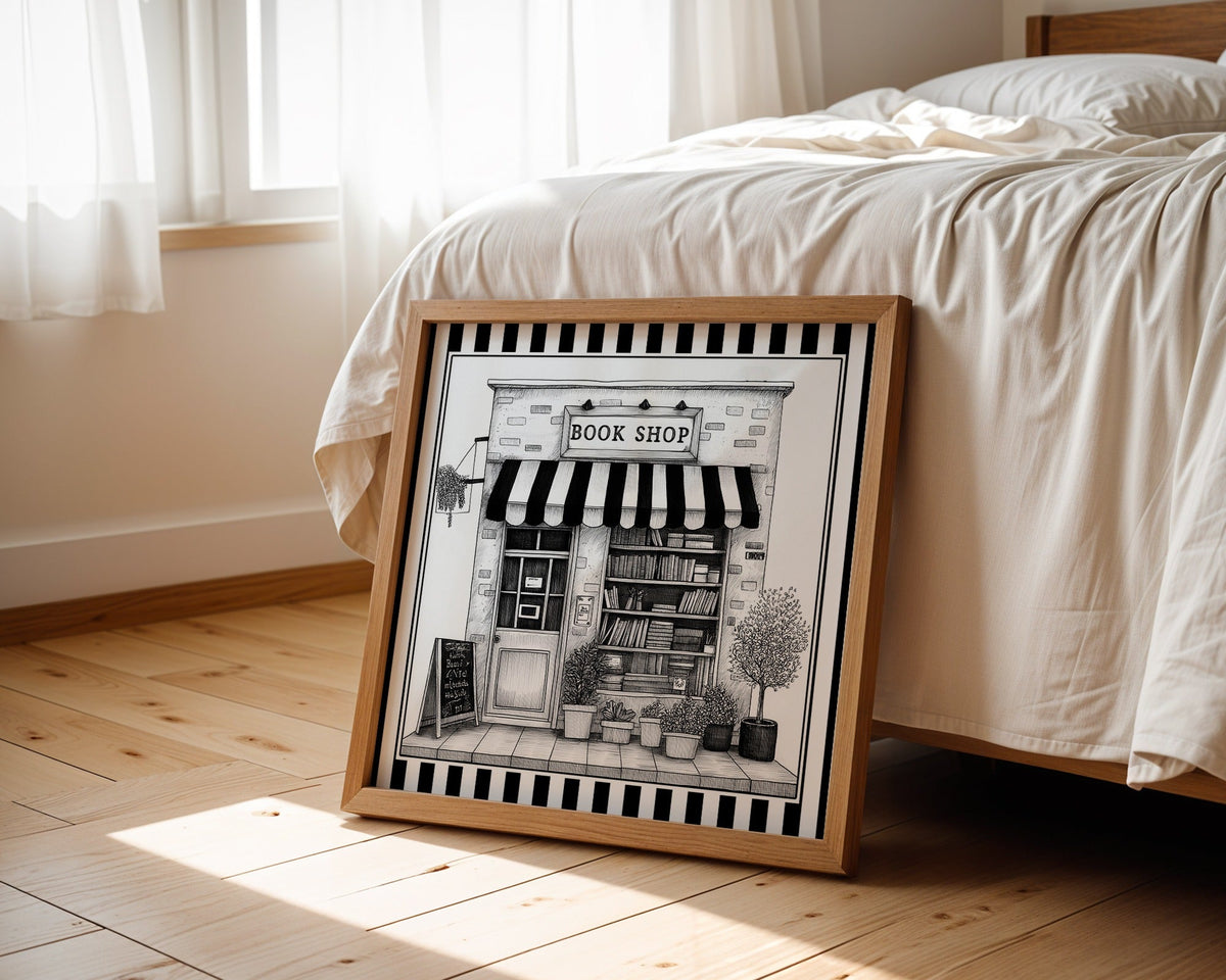 Black and white book shop print displayed beside a bed in a light wood square frame