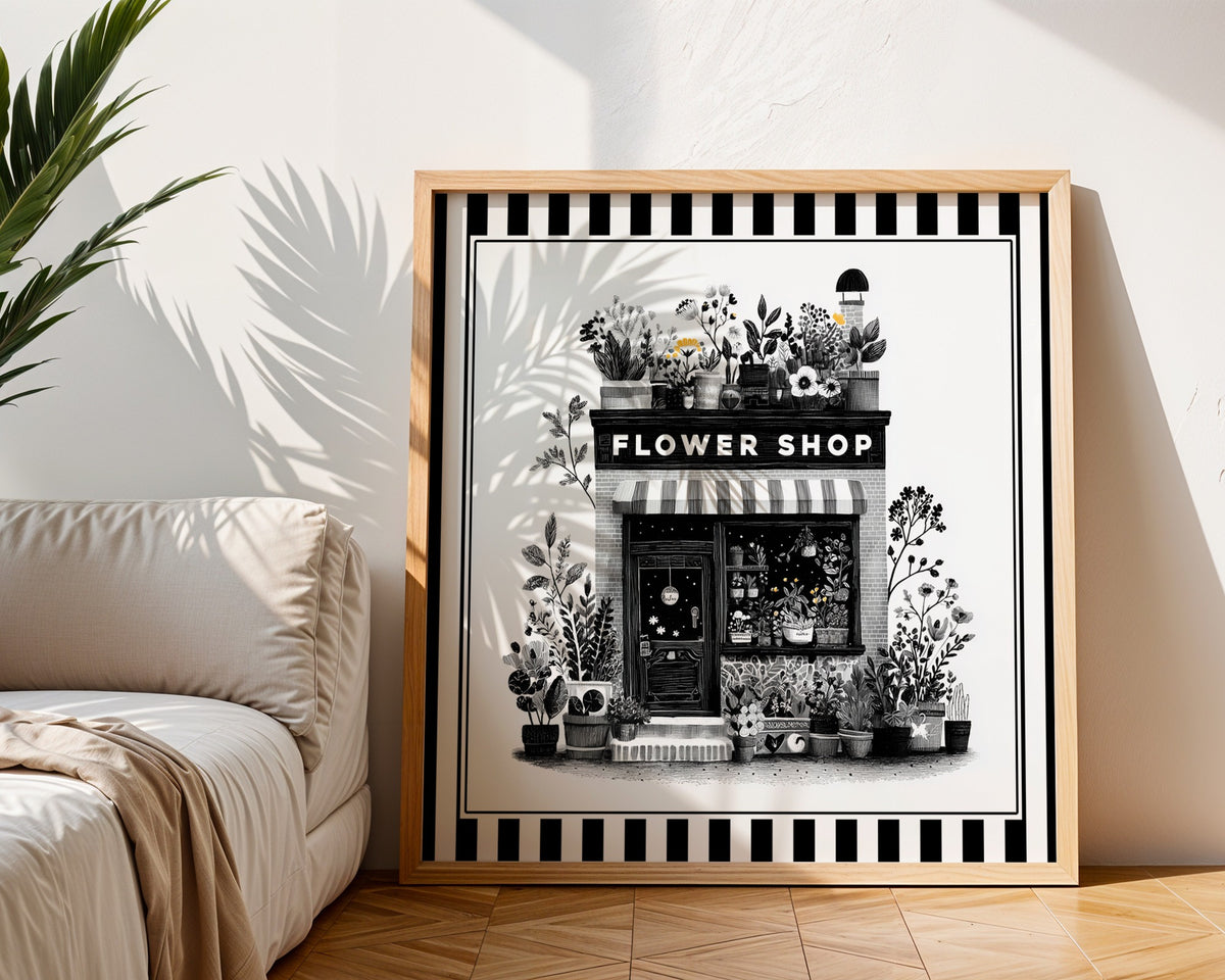 Black and white flower shop print in a light wood frame beside a neutral sofa