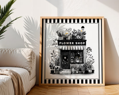 Black and white flower shop print in a light wood frame beside a neutral sofa