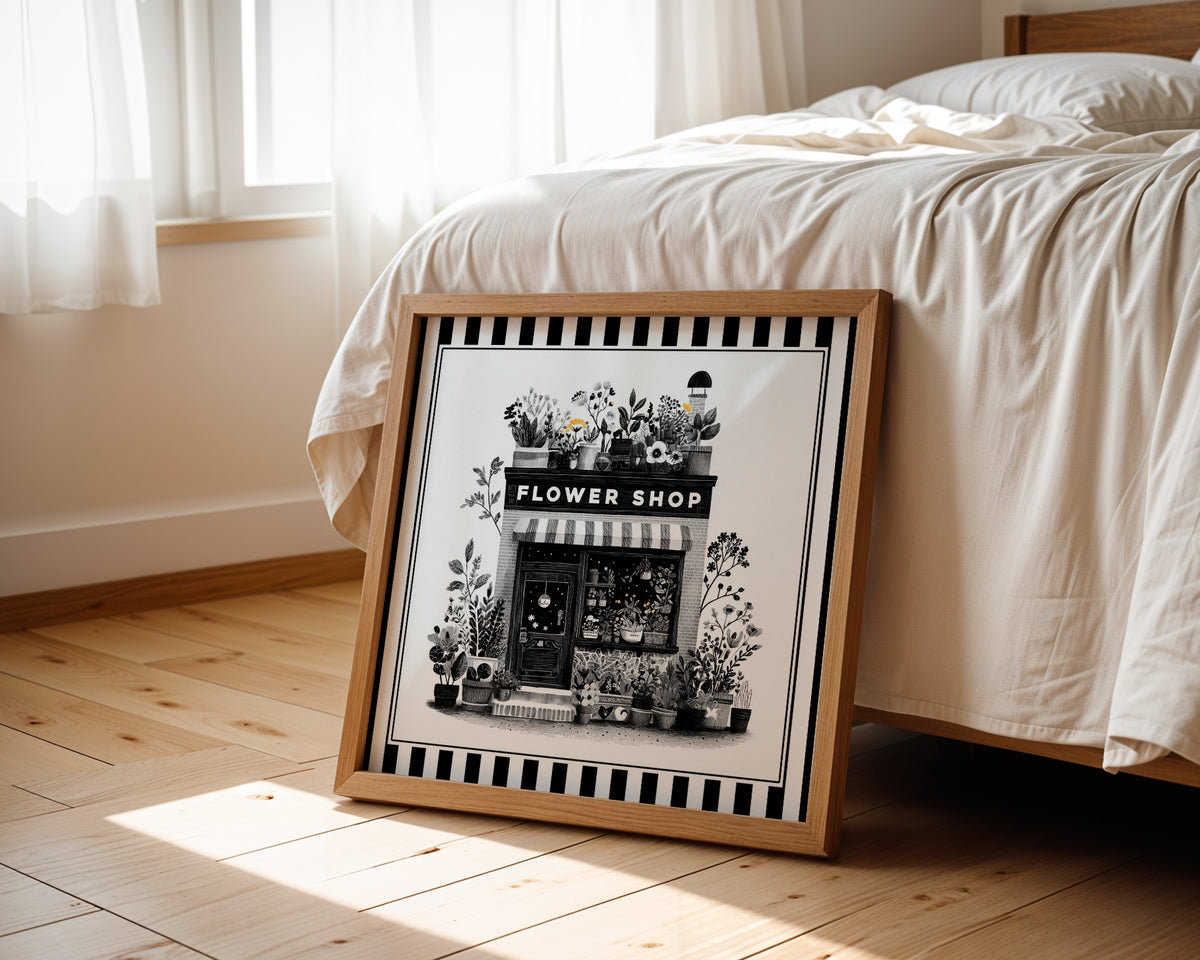 Black and white flower shop wall art displayed beside a bed in a light wood square frame