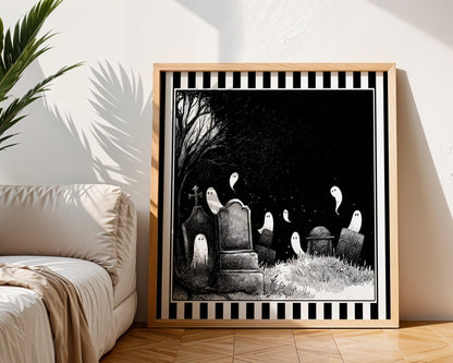 Ghost graveyard print displayed in a light wood square frame beside a neutral sofa