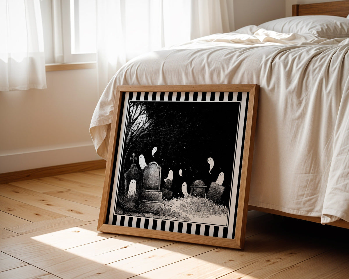 Ghost graveyard print displayed beside a bed in a light wood square frame
