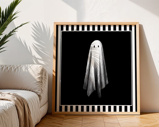 Single white ghost print displayed in a light wood square frame beside a neutral sofa