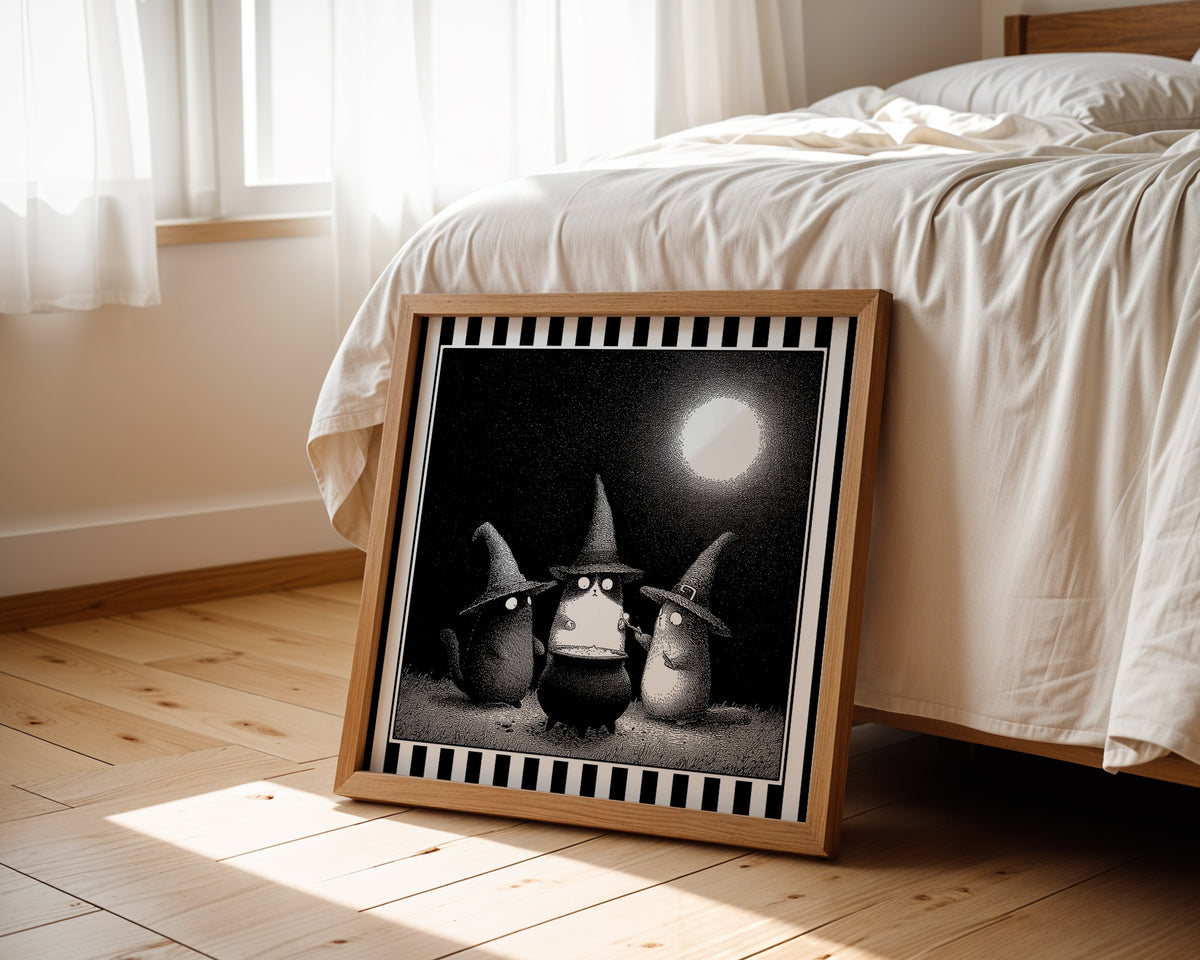 Witch cats moonlit print displayed beside a bed in a light wood square frame